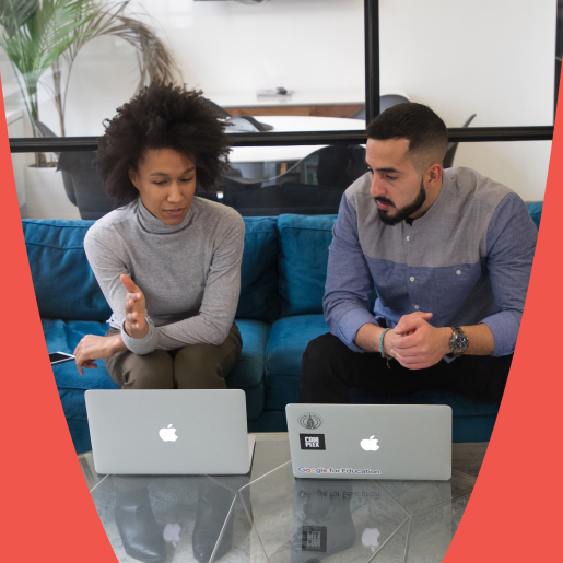 Two colleagues sitting on a modern blue couch with laptops, actively discussing an off-page SEO services project.