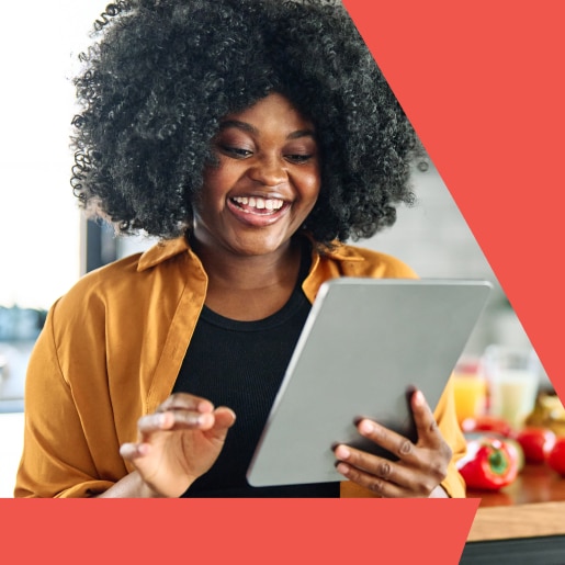 Smiling woman using a digital tablet in a bright kitchen setting.
