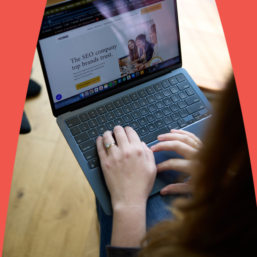Close-up of a person typing on a laptop with a company website open.