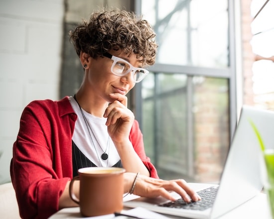 Woman sitting in a minimalist home office, focused on her laptop while exploring technical SEO services