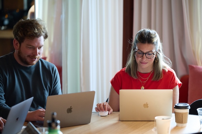 Two people working in a group of people on laptops, possibly focused on AEO optimization planning.