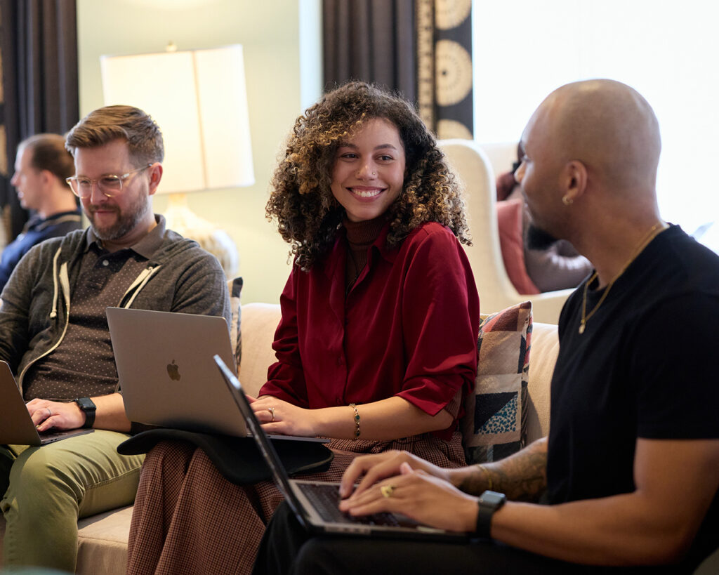 Three members of an SEO firm research competitive keywords on their laptops.