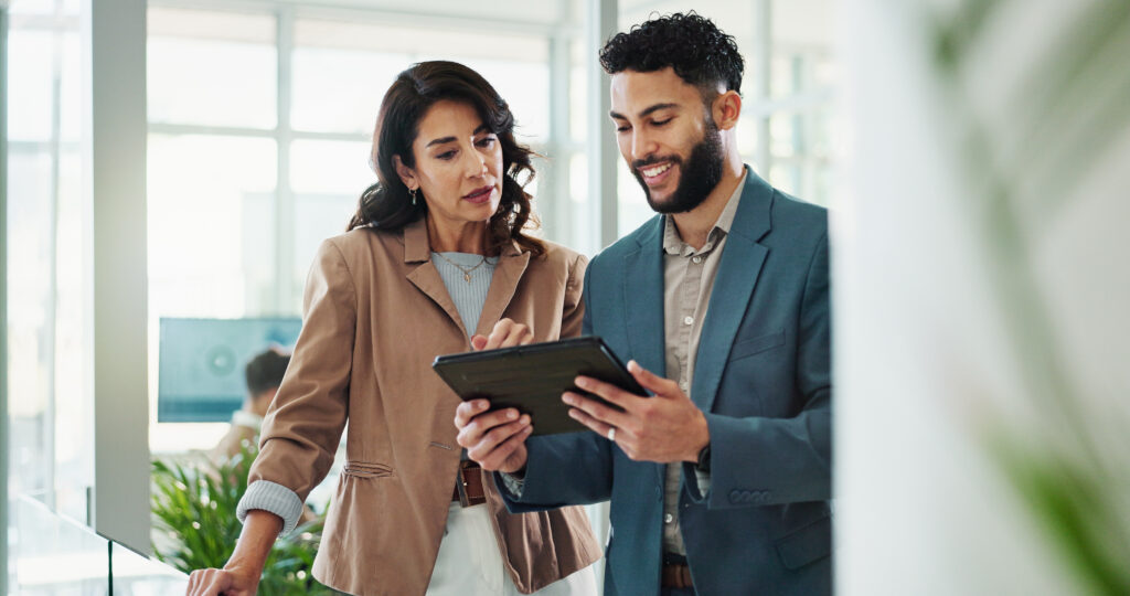 Two people looking at a tablet and discussing their enterprise ecommerce SEO strategy.